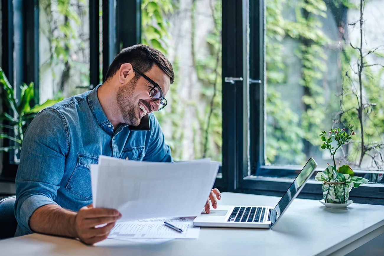 Man achter zijn laptop aan de telefoon, een ondernemer aan het werk.